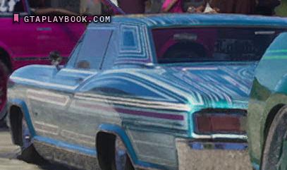 The pale blue lowrider from the rear quarter at 0:27.43: magenta, white and teal scrollwork over the flank and the sail panel, a small opera window framed in it, the sills on the ground, a pink car ahead and a green car behind, an inscription in blackletter on the rear window under the letter floor