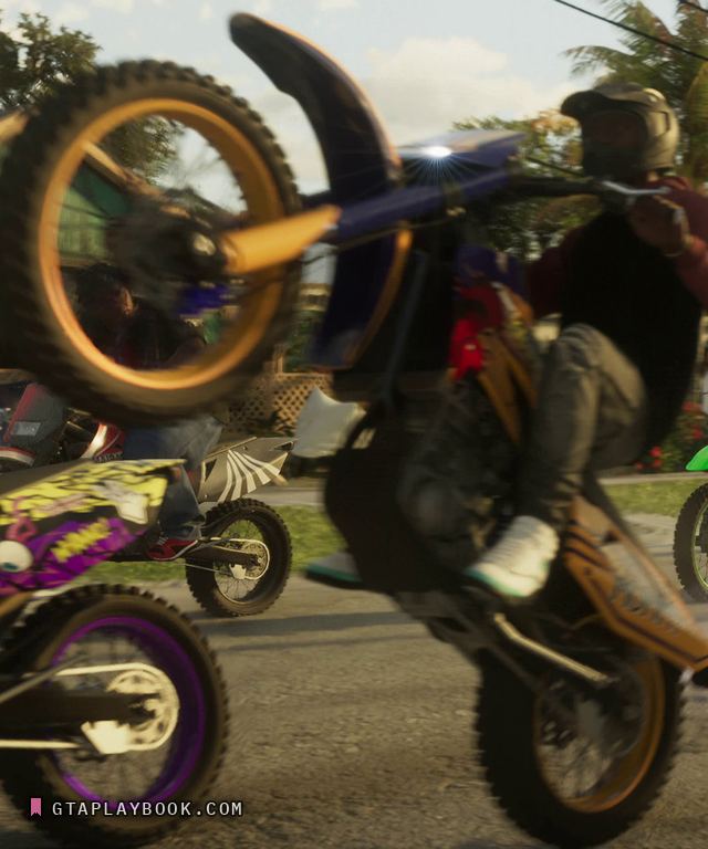 A dirt bike stood almost vertical on its back wheel in a street parade at 1:06.62: gold rims on knobbly tyres, blue-purple mudguard and shrouds, a gold-orange frame, the rider in a maroon top and a tan and black helmet, a bike on purple rims at the left and a green one at the right